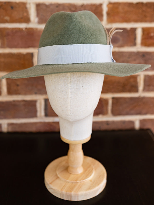 Front view of soft green felt fedora hat with beige coloured feathers.