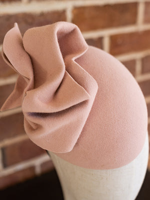 Close up of baby pink felt cocktail hat. The hat has a large felt bow on the top of it.