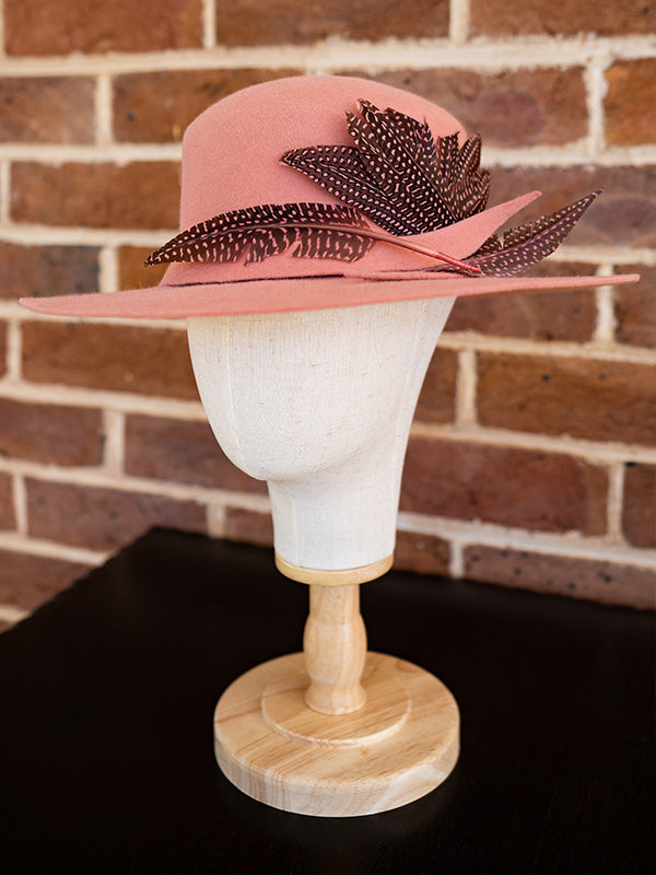 Side view of salmon pink felt hat trimmed with spotty pink dyed feathers.