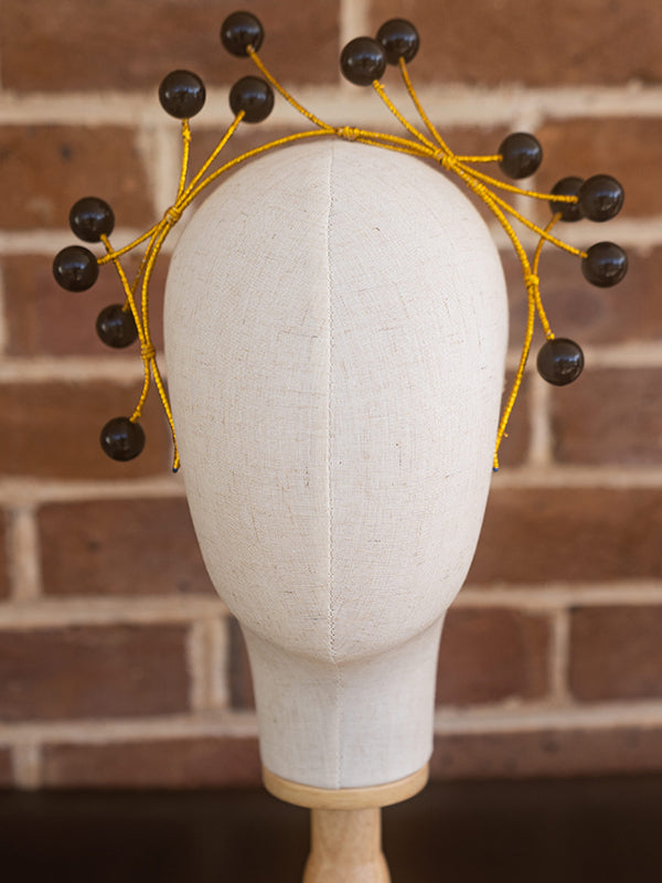 Front view of black beaded headpiece. The beads stand at the end of the headband frame.