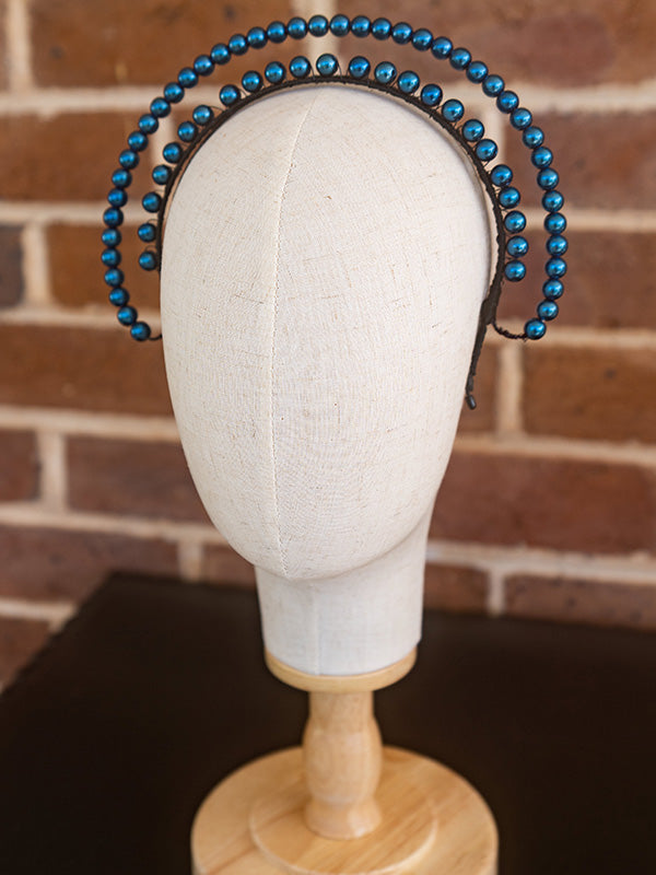 Side view of blue beaded headpiece. The beads sit over two lines and curve around the head.