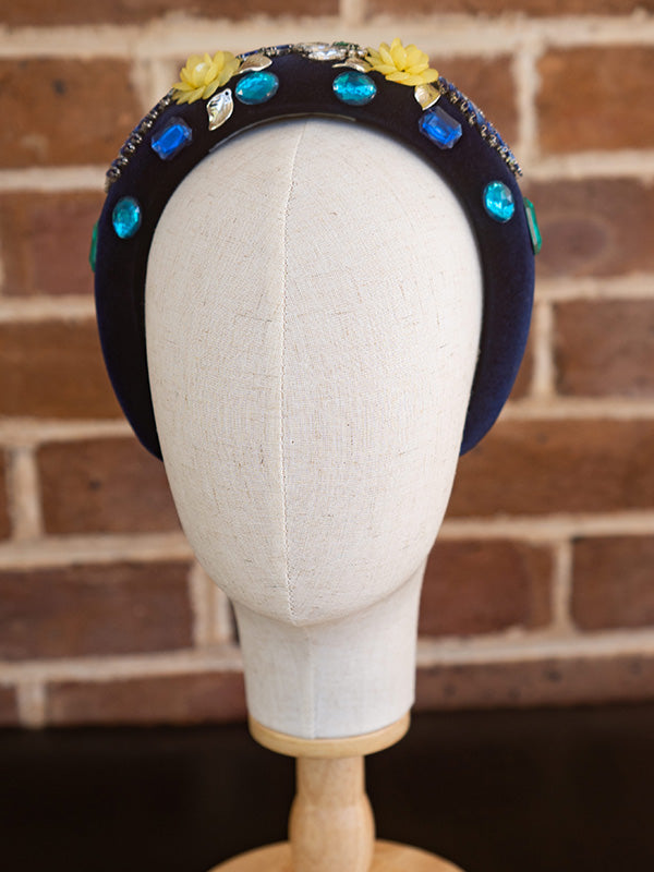 Front view of the blue velvet headband. Colourful beading and gemstone detailing is placed all around the headband.