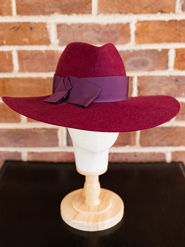 Front view mulberry wide brimmed fedora felt hat with dark red ribbon.