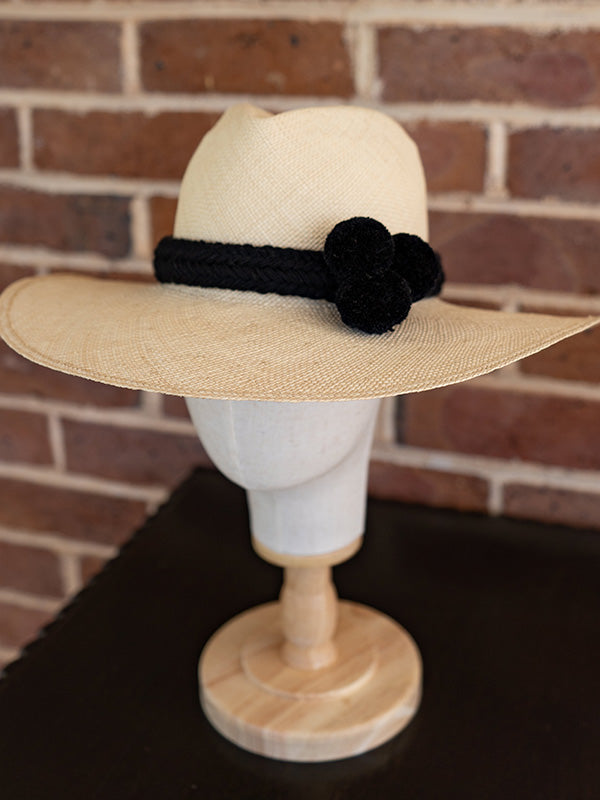 Side view of natural panama fedora hat with black pom pom trim.