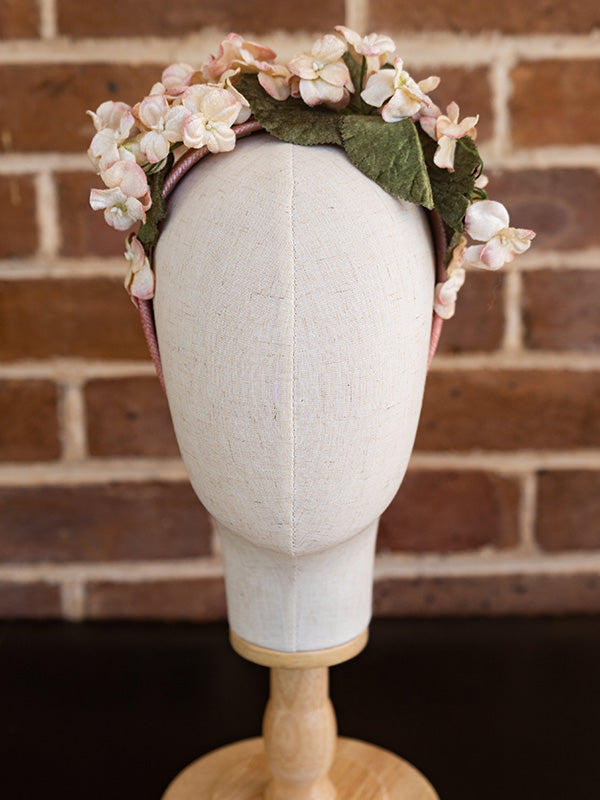 Front view of the vintage inspired floral headband. Vintage style flowers adorn the who headband in dusty pink.
