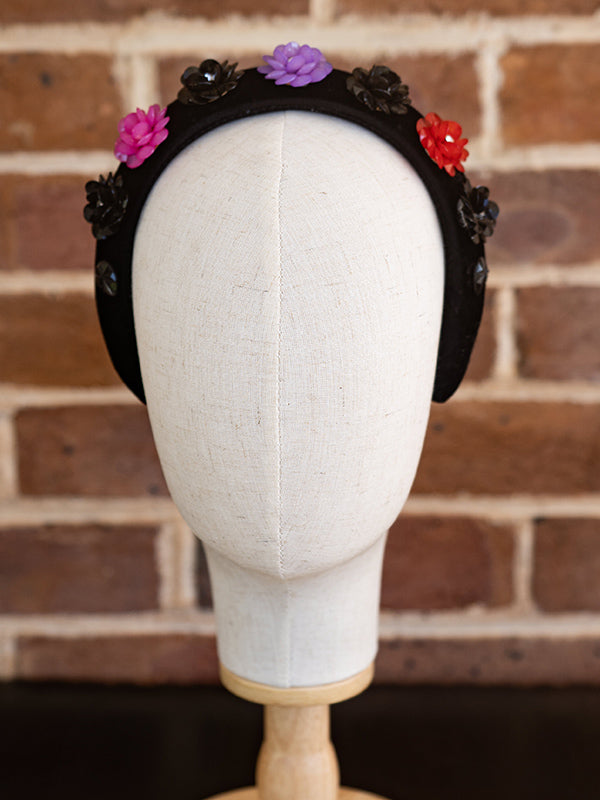 Front view of the black velvet headband. Colourful beads in a floral design cover the headband.