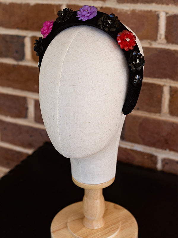 Side view of the black velvet headband. Colourful beads in a floral design cover the headband.
