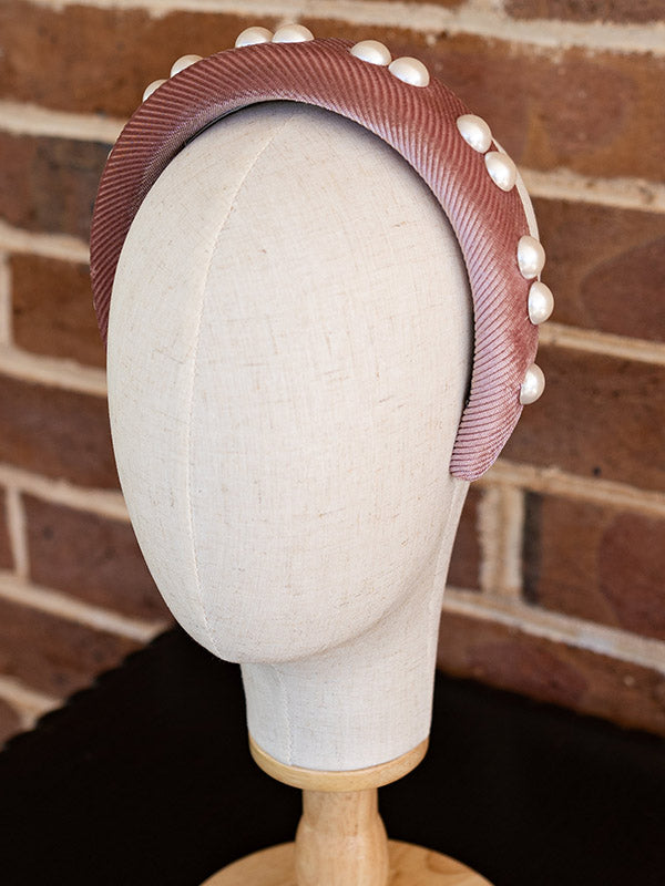 Side view of the dusty pink velvet headband. Faux pearls adorn the headband.