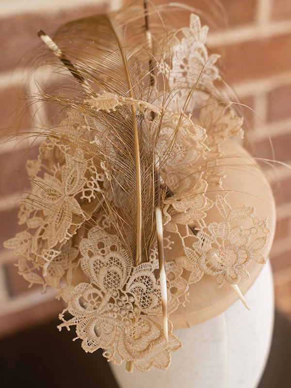 Close up of nude feather, net and lace trimming on top of hat.