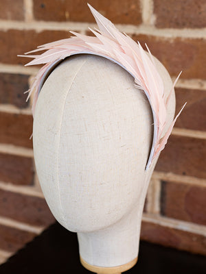 Side view of the soft pink headband. Pink feathers adorn the headband.