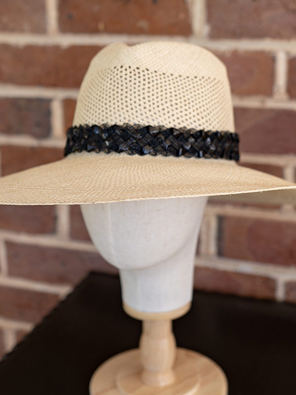 Side view of the wide brimmed natural panama hat and black trim.